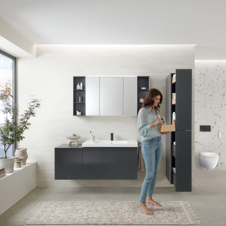 Woman opens tall cabinet with lots of storage space in bathroom Woman opens tall cabinet with lots of storage space in bathroom